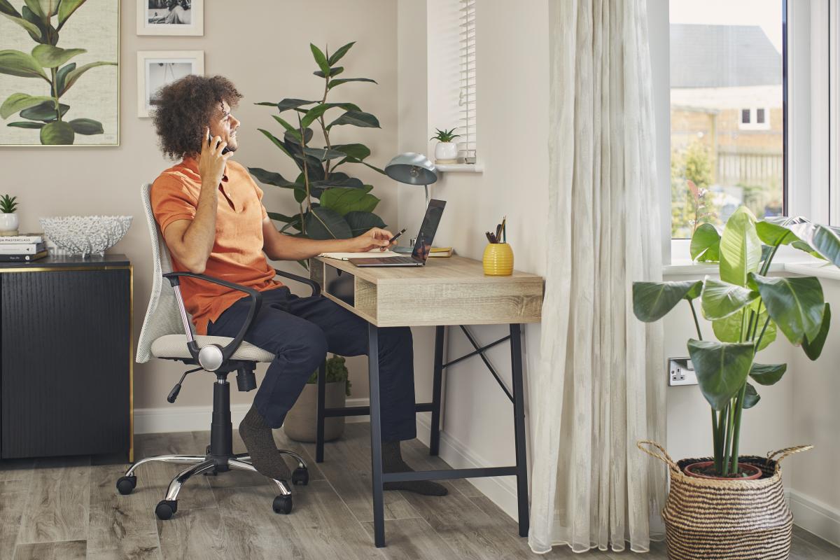 Man sitting at a desk using the phone during a work meeting from his new Bellway home